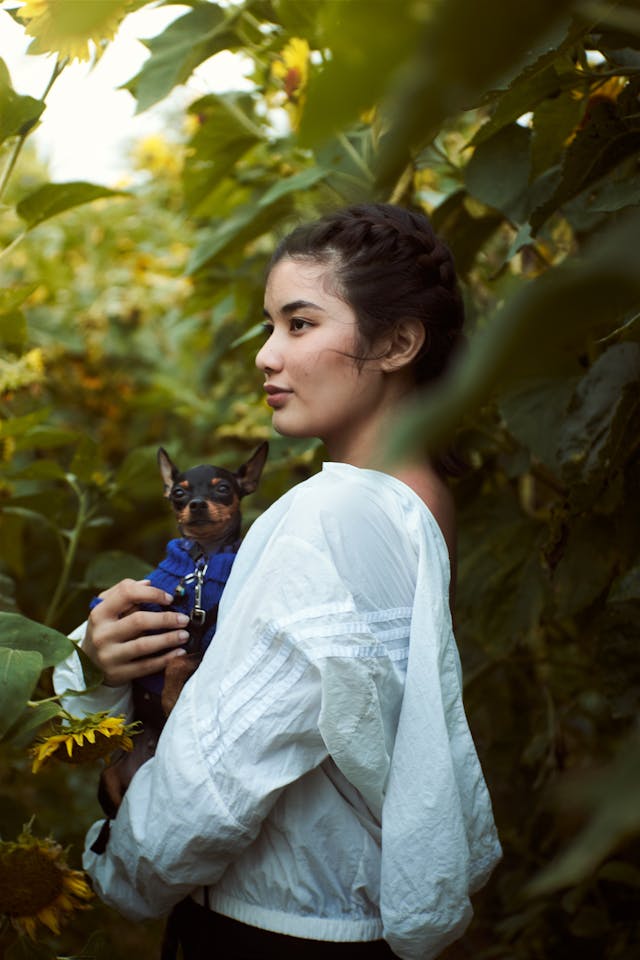 mulher com cão da raça pinscher no colo posando para foto